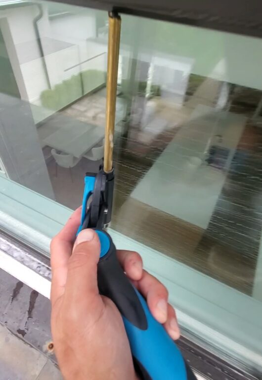 a hand squeegeeing a second story residential window
